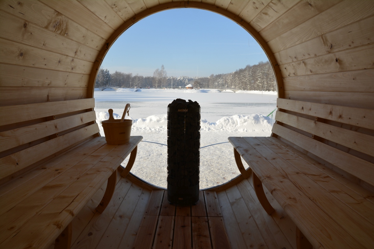 Widok na główną komorę sauny, w tle okno panoramiczne z widokiem na zbiornik wodny w zimowej scenerii.